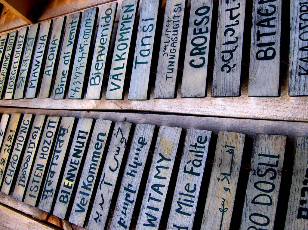 "Welcome" in many languages on a wooden background.